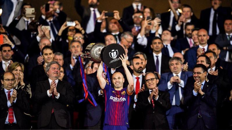 Andres Iniesta hoists the Copa del Rey trophy above his head in joy.