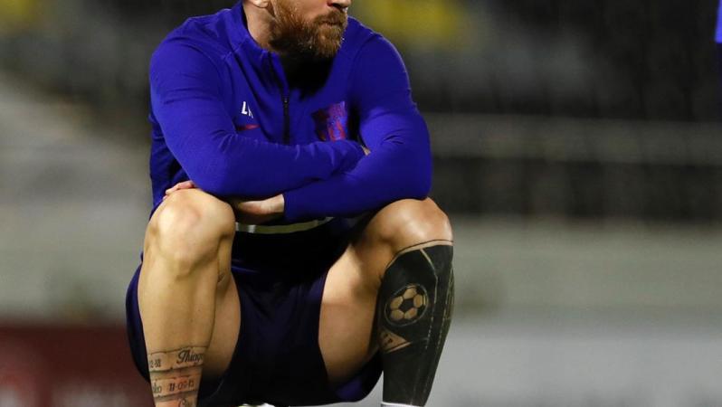 Messi sits on soccer ball.