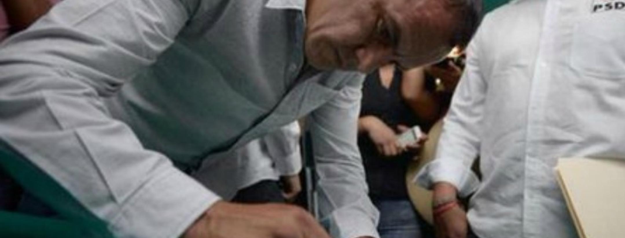 Blanco is shown in a dress shirt, signing autographs.