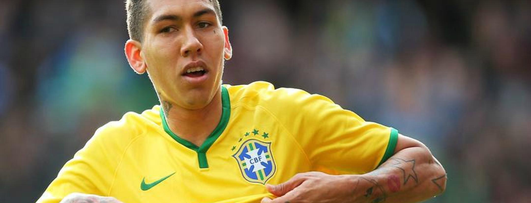 Roberto Firmino in the act of taking his shirt off after scoring for Brazil. 