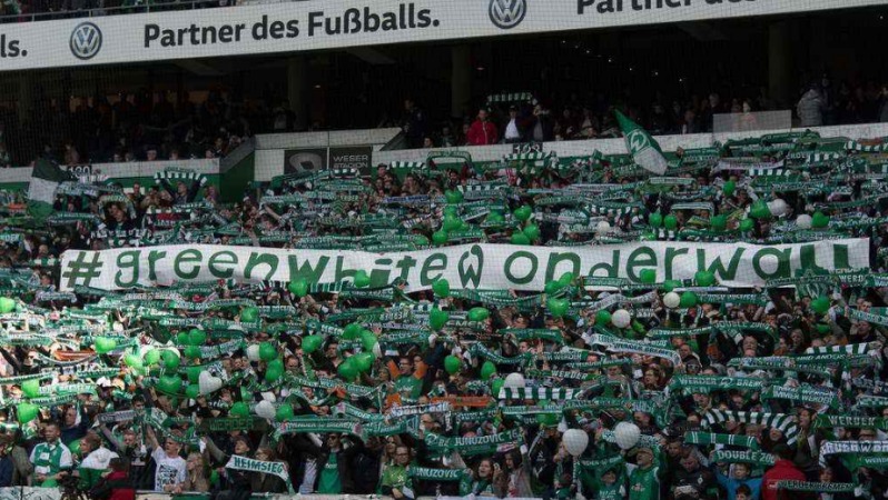 Fans of Werder Bremen hold up a giant tifo with #GreenWhiteWonderwall